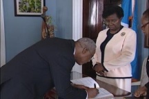 Justice Rawlins signs after taking the Oath of Office, while GG Dame Pearlette Louisy looks on