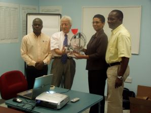 Mr Naohito Ichiryu of JICA hands over the EWS to Director NEMO watched by officials of UWI