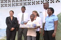Micoud Sec's Henry Somain posses with officials, holding prize awarded by Lady Compton for topping Common Entrance in his district